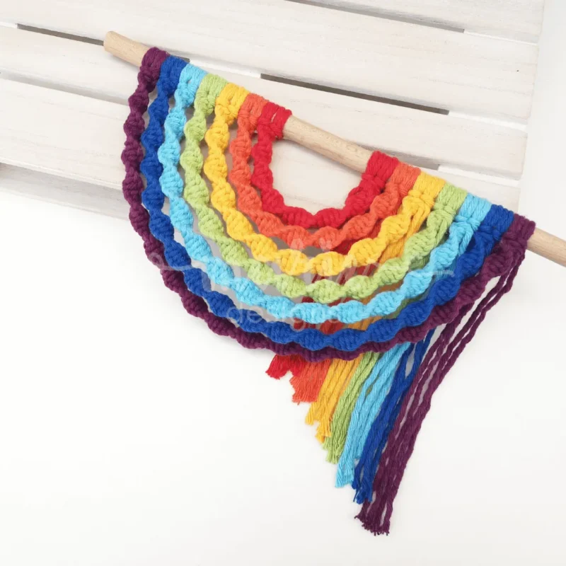 Arco-Íris em macramé com design invertido e fios vibrantes, ideal para decoração de quartos, paredes ou eventos como baby showers