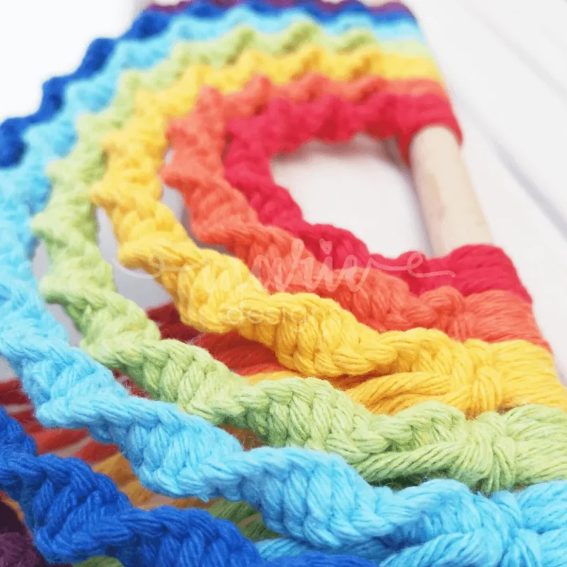 Arco-Íris em macramé com design invertido e fios vibrantes, ideal para decoração de quartos, paredes ou eventos como baby showers