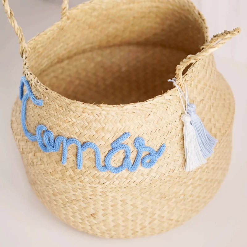 Cesto redondo personalizado em palha natural com o nome 'Tomás' em corda azul, ideal para organização e decoração de quartos de bebé