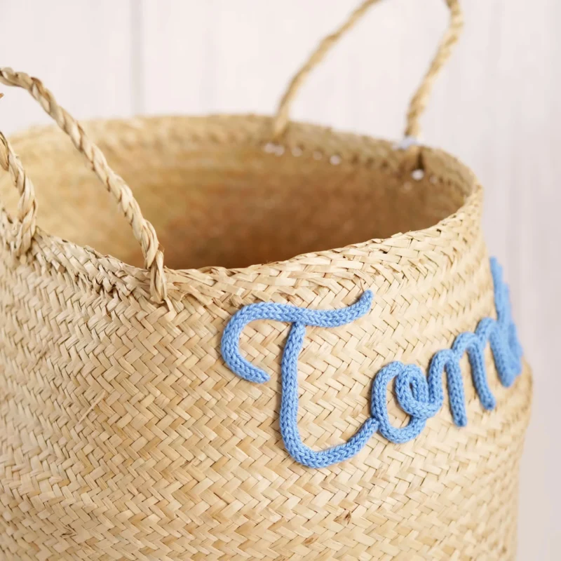 Cesto redondo personalizado em palha natural com o nome 'Tomás' em corda azul, ideal para organização e decoração de quartos de bebé