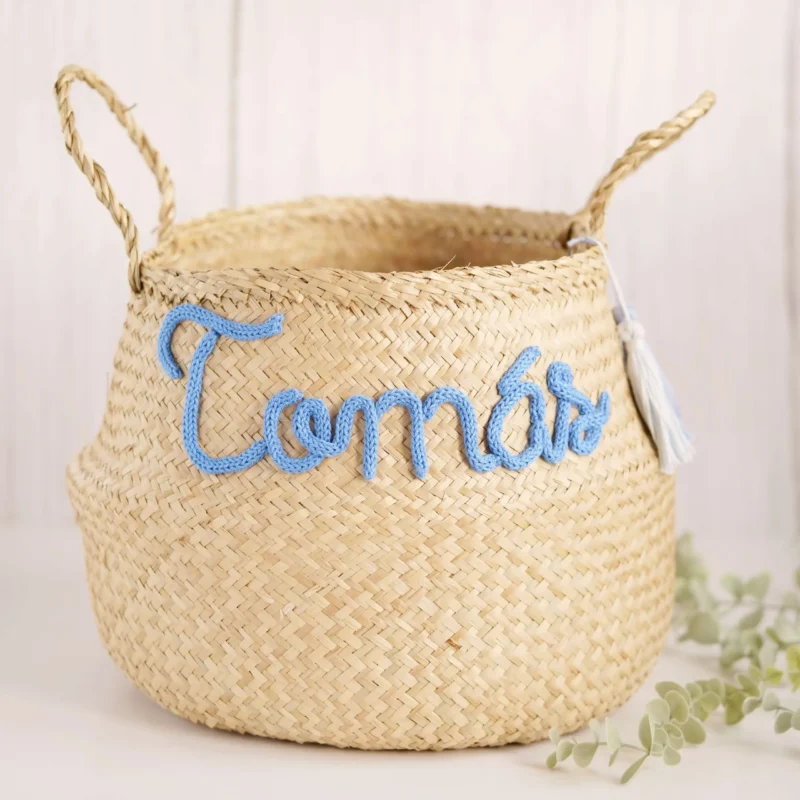 Cesto redondo personalizado em palha natural com o nome 'Tomás' em corda azul, ideal para organização e decoração de quartos de bebé