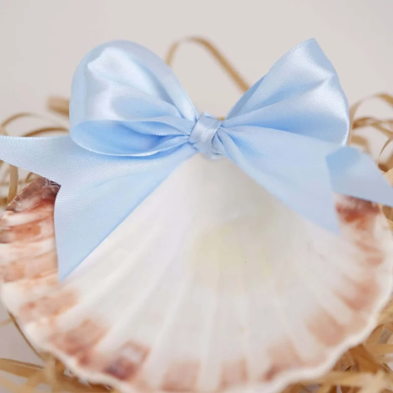 Concha de batismo com acabamento natural, decorada com um laço em fita de cetim