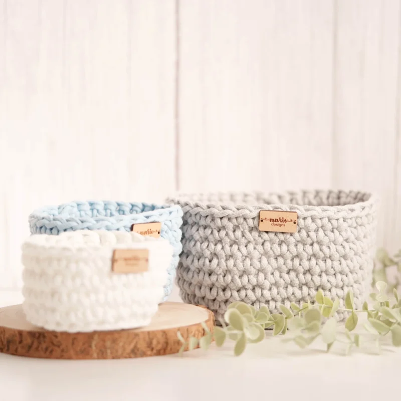 Conjunto de três cestos feitos à mão em crochet, em tons pastel, com uma estética decorativa e funcional
