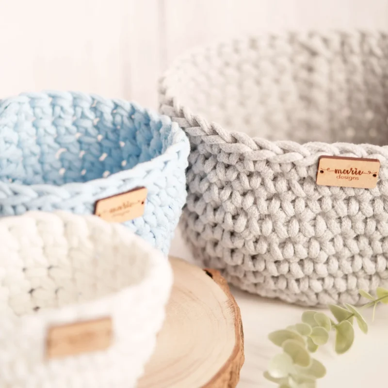 Conjunto de três cestos feitos à mão em crochet, em tons pastel, com uma estética decorativa e funcional