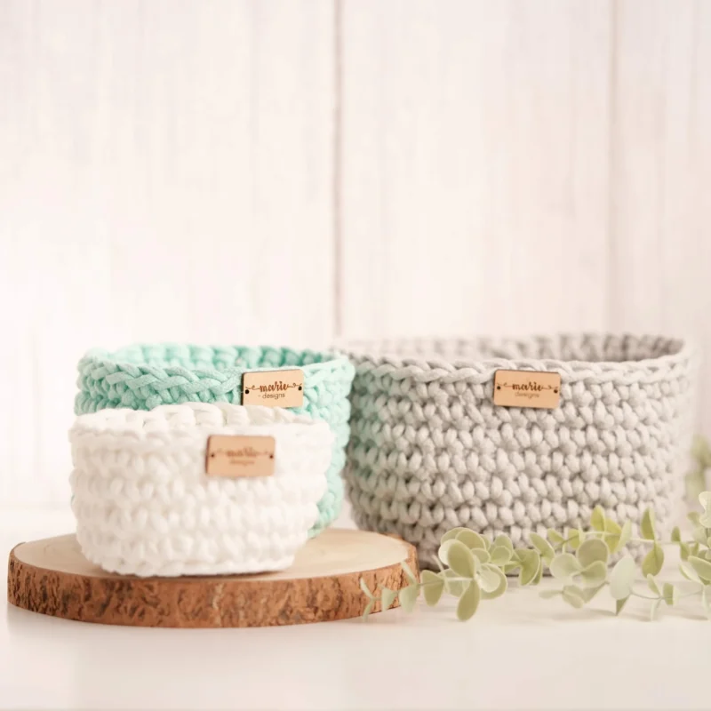 Conjunto de três cestos feitos à mão em crochet, em tons pastel, com uma estética decorativa e funcional