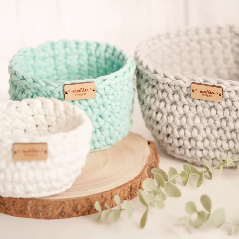 Conjunto de três cestos feitos à mão em crochet, em tons pastel, com uma estética decorativa e funcional