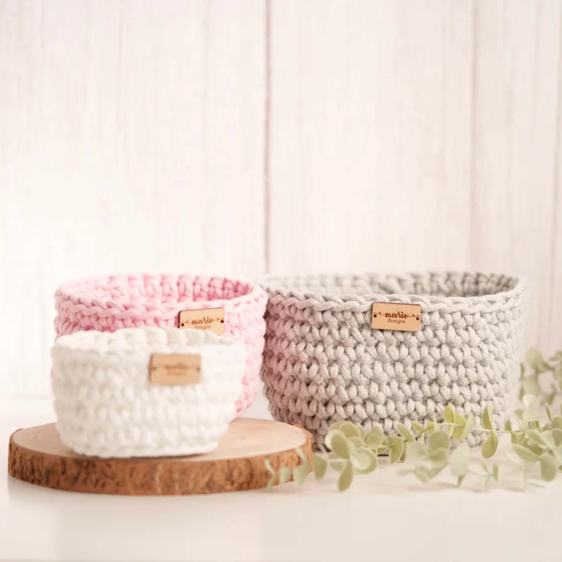Conjunto de três cestos feitos à mão em crochet, em tons pastel, com uma estética decorativa e funcional