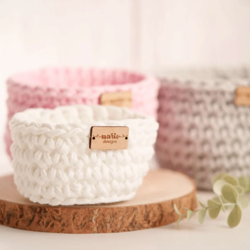 Conjunto de três cestos feitos à mão em crochet, em tons pastel, com uma estética decorativa e funcional