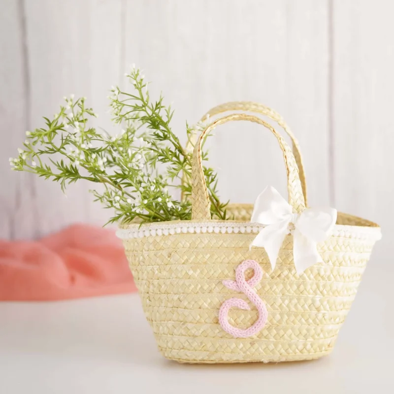 Mala de palha para criança decorada com inicial em crochet, laço branco e detalhes delicados