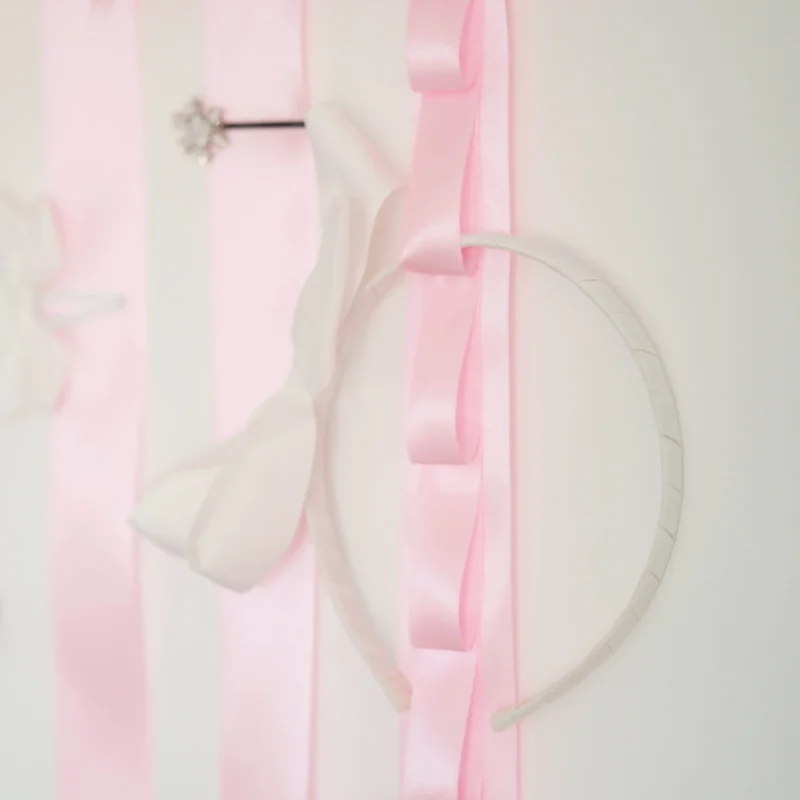 Porta laços em formato de nuvem branca com fitas de cetim rosa, detalhes de laços decorativos e espaço para organizar acessórios infantis