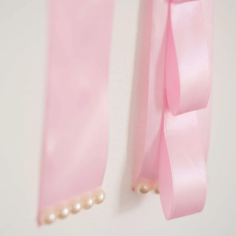 Porta laços em formato de nuvem branca com fitas de cetim rosa, detalhes de laços decorativos e espaço para organizar acessórios infantis