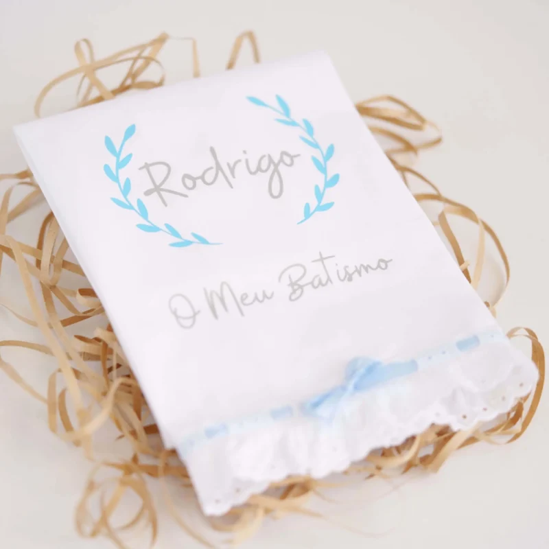 Toalha de Batismo personalizada com estampagem, decorada com renda e um laço delicado, exibindo o nome da criança e a frase 'O Meu Batismo'