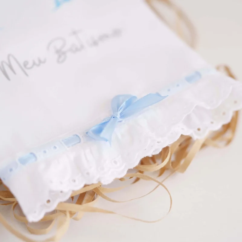 Toalha de Batismo personalizada com estampagem, decorada com renda e um laço delicado, exibindo o nome da criança e a frase 'O Meu Batismo'
