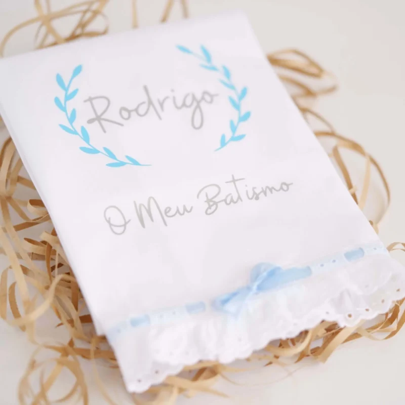 Toalha de Batismo personalizada com estampagem, decorada com renda e um laço delicado, exibindo o nome da criança e a frase 'O Meu Batismo'