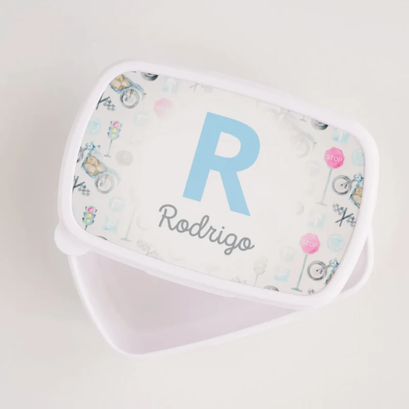 Lancheira personalizada branca com tampa decorada com inicial e nome “Rodrigo” em azul, rodeada por ilustrações coloridas